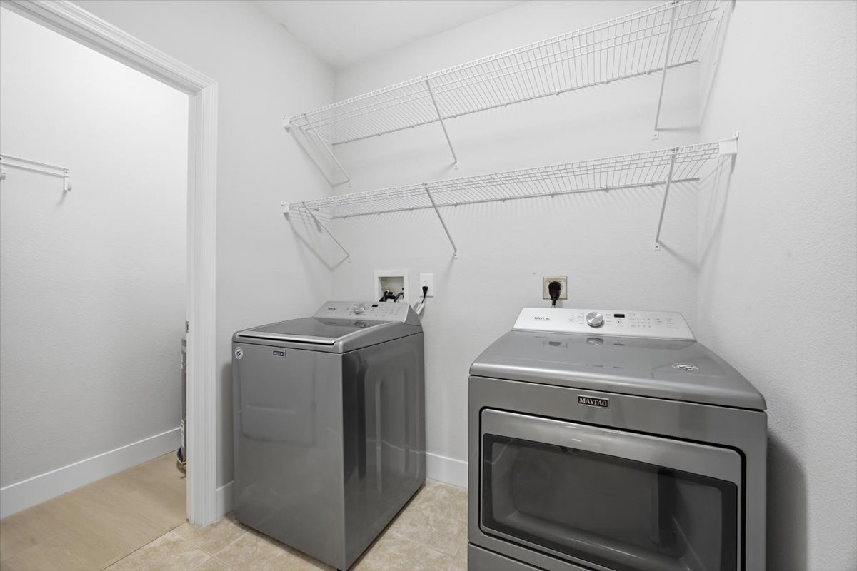 Interior laundry room with full-size Maytag washer and dryer